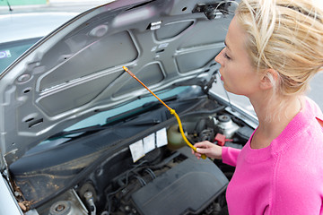 Image showing Woman inspecting broken car engine.