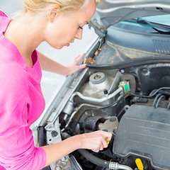 Image showing Woman inspecting broken car engine.