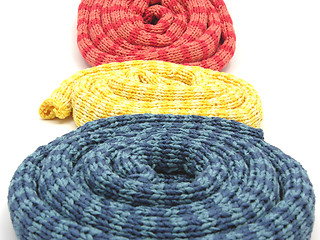 Image showing Three striped reeled up knitting scarfs on white