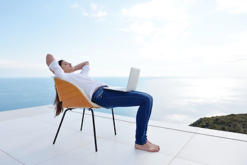 Image showing relaxed young woman at home working on laptop