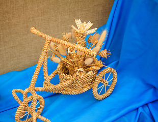 Image showing The original souvenir made of wattled straw against blue silk.