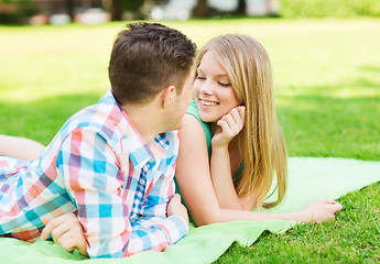 Image showing smiling couple lying on blanket in park