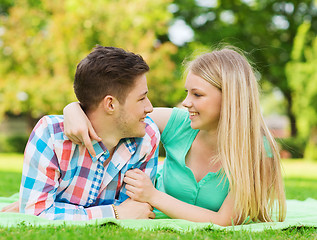 Image showing smiling couple lying on blanket in park