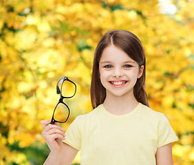 Image showing smiling cute little girl holding black eyeglasses