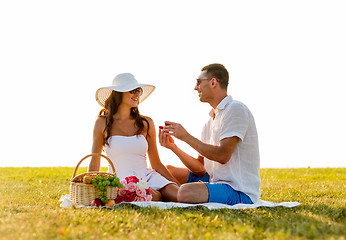 Image showing smiling couple with small red gift box on picnic