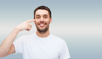 Image showing smiling young handsome man pointing to eyes