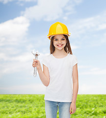 Image showing smiling little girl in hardhat with wrench