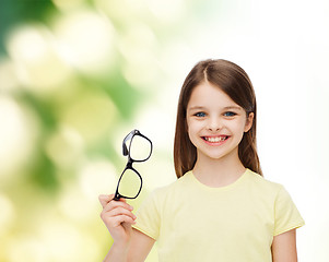 Image showing smiling cute little girl holding black eyeglasses