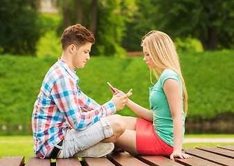 Image showing couple with smartphones sitting on bench in park