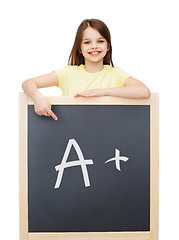 Image showing happy little girl pointing finger to blackboard