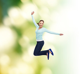 Image showing smiling young woman jumping in air