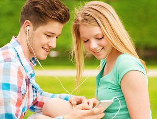 Image showing smiling couple with smartphone and earphones
