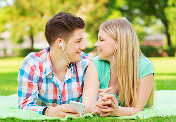 Image showing smiling couple with smartphone and earphones