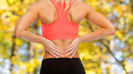 Image showing close up of sporty woman touching her back