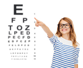 Image showing cute little girl in eyeglasses pointing in the air