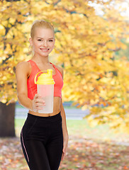 Image showing smiling sporty woman with protein shake bottle