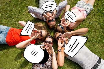 Image showing group of smiling friends lying on grass outdoors