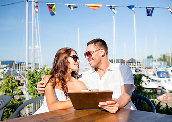 Image showing smiling couple with menu at cafe
