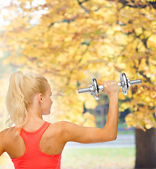 Image showing sporty woman with heavy steel dumbbell from back