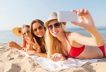 Image showing group of smiling women with smartphone on beach