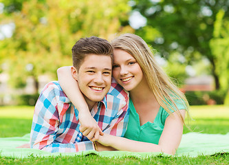 Image showing smiling couple lying on blanket in park