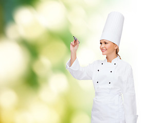 Image showing smiling female chef writing something on air