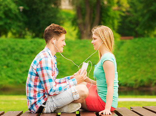 Image showing smiling couple with smartphone and earphones