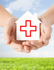 Image showing hands holding paper house with red cross