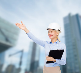 Image showing smiling businesswoman in helmet with clipboard