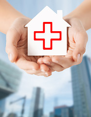 Image showing hands holding paper house with red cross