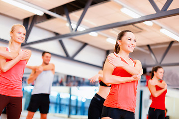 Image showing group of smiling people stretching in the gym