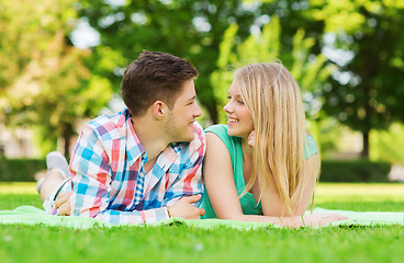 Image showing smiling couple lying on blanket in park