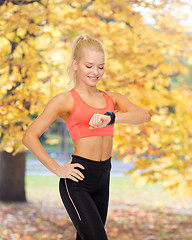 Image showing smiling woman with heart rate monitor on hand