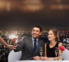 Image showing smiling couple paying for dinner with credit card