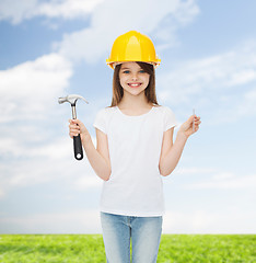 Image showing smiling little girl in hardhat with hammer