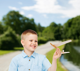 Image showing smiling little boy holding a wooden airplane model