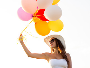 Image showing smiling young woman in sunglasses with balloons