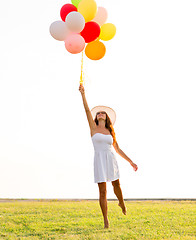 Image showing smiling young woman in sunglasses with balloons