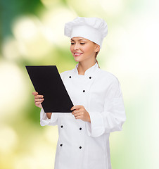 Image showing smiling female chef with black blank paper