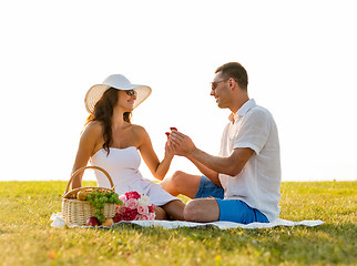 Image showing smiling couple with small red gift box on picnic