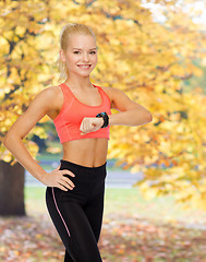 Image showing smiling woman with heart rate monitor on hand