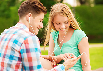 Image showing smiling couple with smartphone and earphones