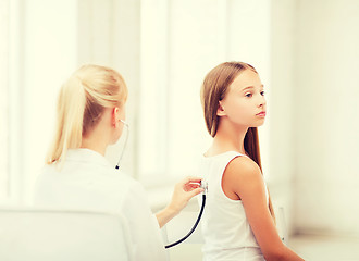 Image showing doctor with stethoscope listening to the patient