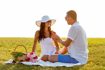 Image showing smiling couple with small red gift box on picnic