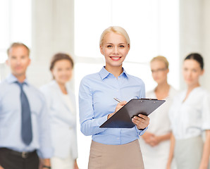 Image showing smiling businesswoman with clipboard and pen