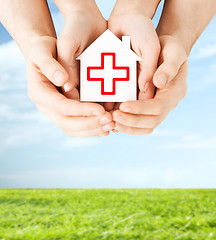 Image showing hands holding paper house with red cross