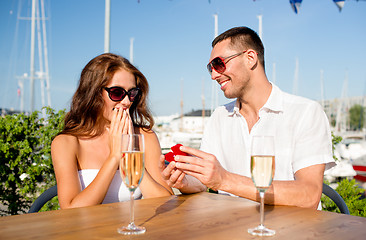 Image showing smiling couple with champagne and gift at cafe