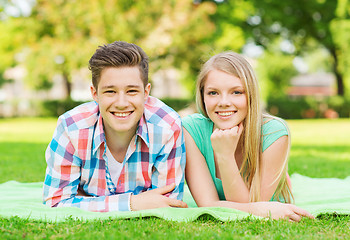 Image showing smiling couple lying on blanket in park