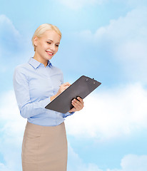 Image showing smiling businesswoman with clipboard and pen