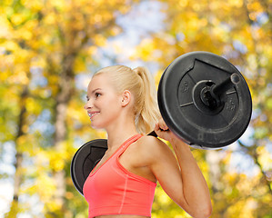 Image showing smiling sporty woman exercising with barbell